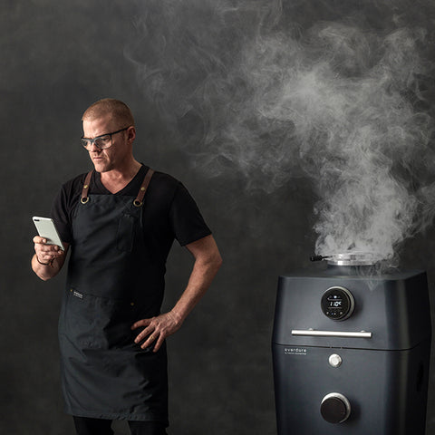 sfeerbeeld van de Everdure 4K met een staande Heston Blumenthal die op zijn telefoon kijkt in het graphite te koop bij My Cool Kitchen